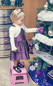 装饰圣诞树的金发小女孩图片