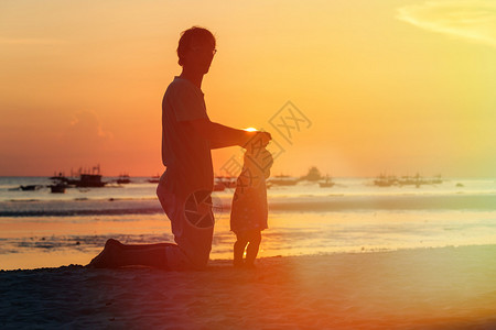 日落海滩上父亲和小女儿的剪影图片