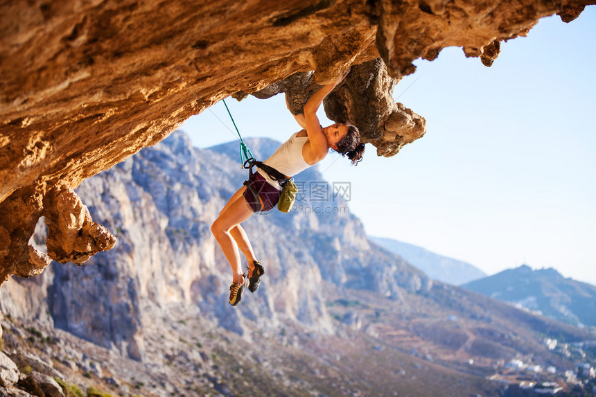 年轻女攀岩在悬崖上图片