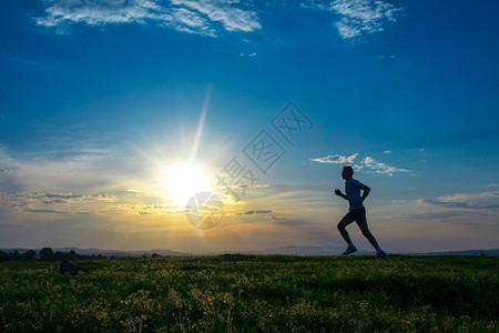 在草地上奔跑日出日落的天空在背景之下赛马手图片
