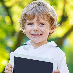 可爱的快乐的小男孩拿着平板电脑图片