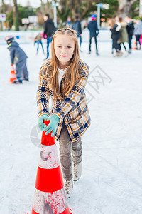 可爱的小女孩学习滑冰在一个愉快的冬天图片