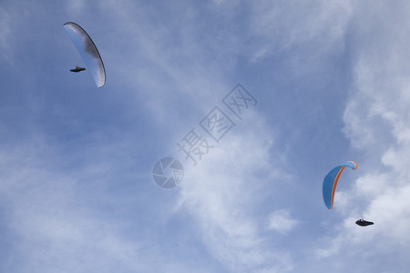 白色和蓝色滑翔伞在满云白蓝天图片