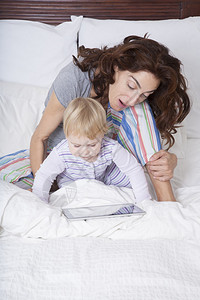 十八个月金发婴儿金发宝黑褐色女人妈在白床上看图片
