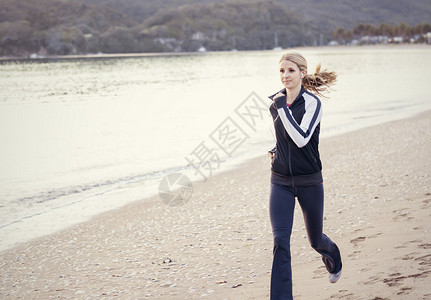 沿着海滩奔跑的年轻女子图片