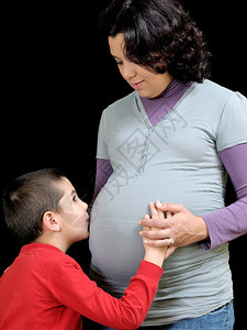 怀着一个小儿子的孕妇拥抱和亲吻腹部图片