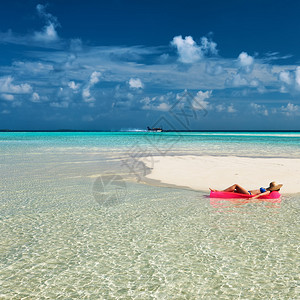 女人在沙滩水上的充气床垫上放松图片