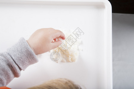17个月的金发caucasian婴儿橙色双边灰色毛衣用她的手用白图片