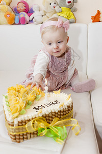 蹒跚学步的女孩和她的生日蛋糕的肖像图片