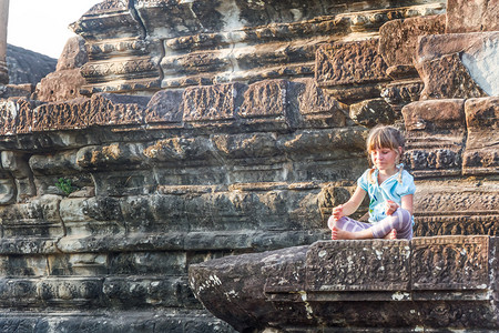 在柬埔寨吴哥窟冥想的年轻快乐儿童女孩游客图片