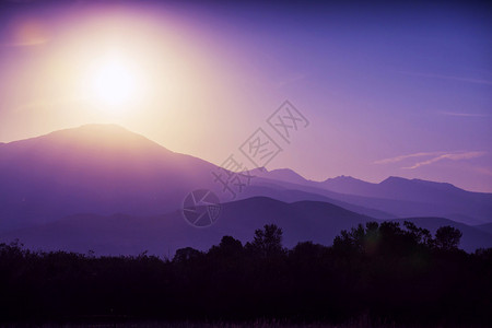 日出时的山剪影与紫色太阳光图片