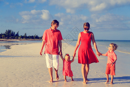 年轻的家庭两个孩子在沙滩上散步图片