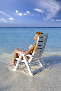 年轻漂亮的女人在海边的沙滩椅上图片