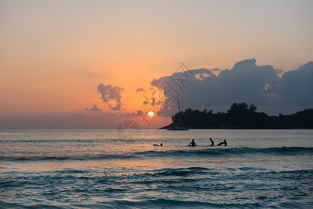 日落时男孩在海边冲浪板上冲浪的剪影图片