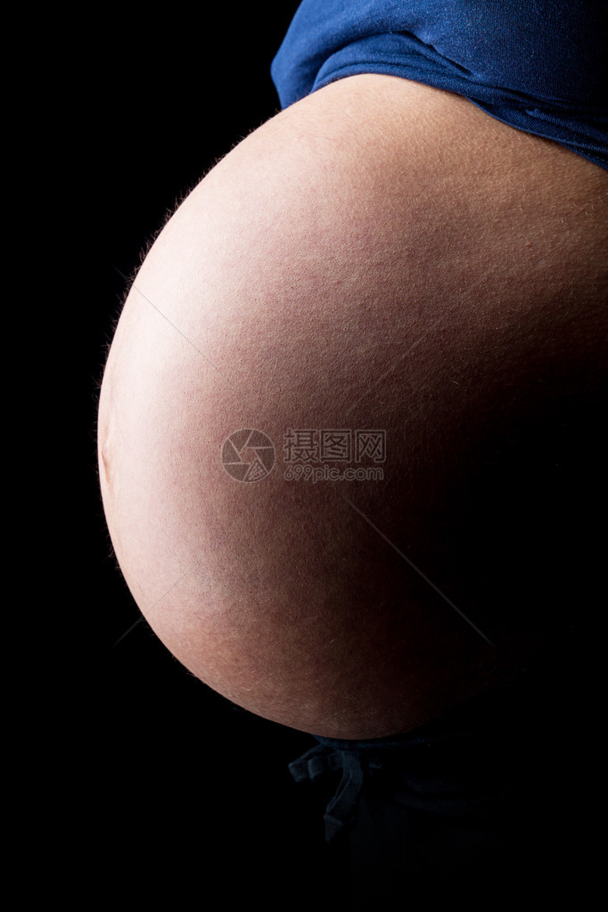 孕妇的腹部是黑色背景在工作室里被带图片