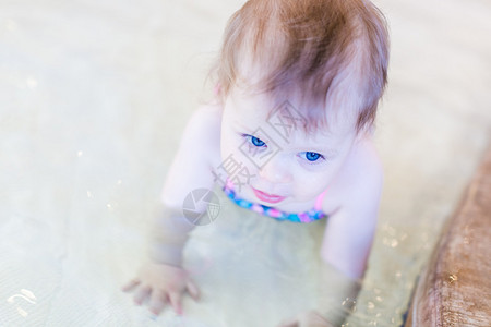 可爱的女婴在室内游泳池游泳背景图片