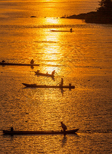 许多渔民乘游艇在日落时捕鱼Silh图片