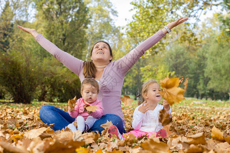 快乐的母亲与两个女儿在公园里享受美丽的秋日幸福家庭无忧虑放图片