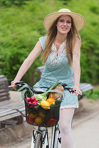 有魅力的金发美女戴着草帽骑着自行车图片