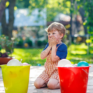 金发小男孩在夏日花园里玩泼水孩子制作水弹和家人一起玩在炎热的夏日与孩子们图片