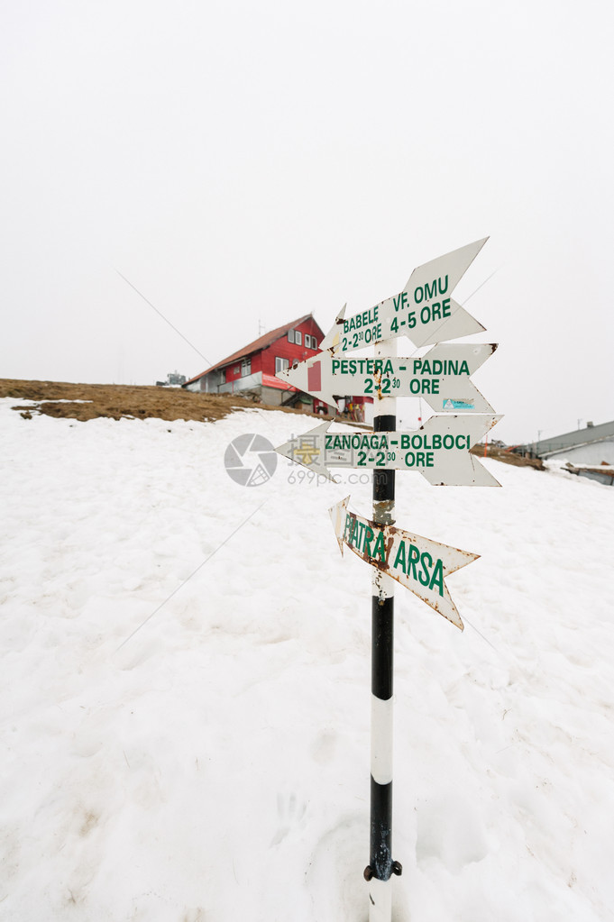 罗马尼亚滑雪度假村上方雪地中的木制路标图片