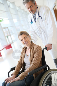 医生在手术后与坐在轮椅上的女人交谈图片
