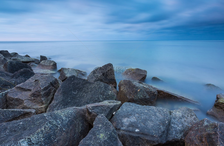 美丽的波罗的海与石防波堤宁静的长时间曝光景观与喜怒无常的图片