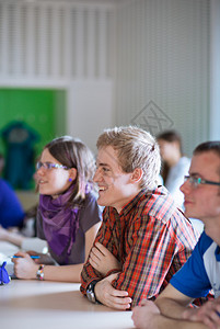 英俊的大学生在课堂上坐在满是学生的教室里图片