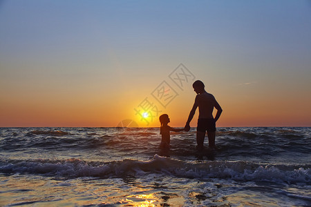 父亲和女儿崇拜海边的日落图片