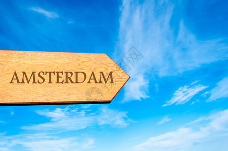 Wooden箭头标志指向目的地AMSTERDAM对抗清蓝天空图片