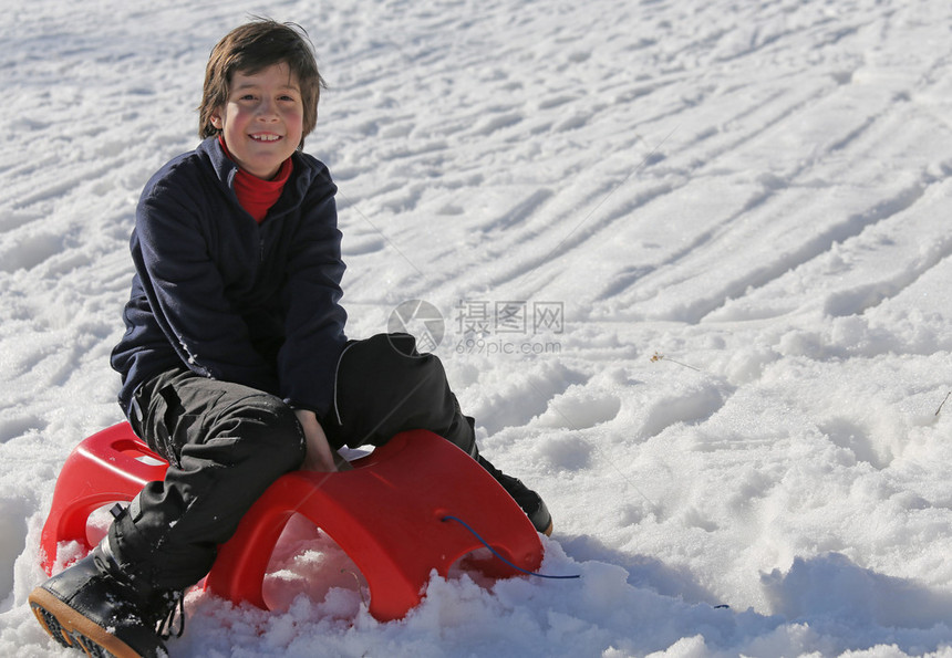 小男孩在冬天的山上红雪图片