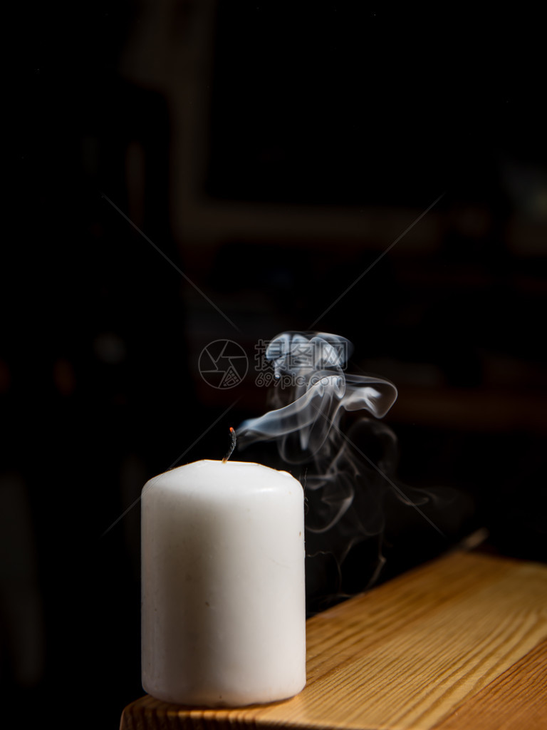 来自深色背景的吹灭蜡烛的烟雾图片