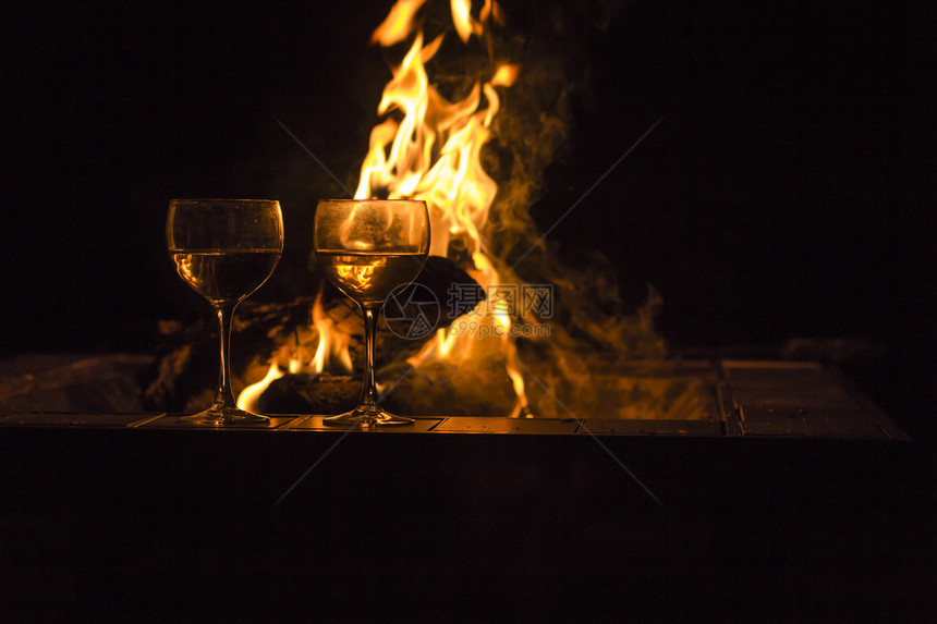 两杯葡萄酒由营火旁的两杯红酒在这张闪亮图片