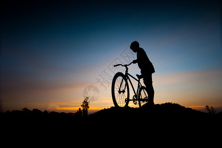 日落时儿童和自行车的剪影图片