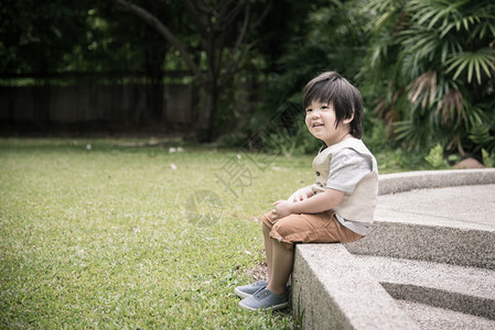 小亚洲男孩坐在公园里思考图片