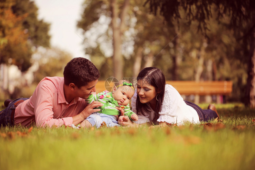 父母带着女婴坐在公园的草地上图片