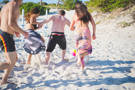 夏季在海滩上玩球的男女青年多种族朋友团体图片