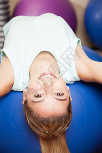 在健身房用健身球做伸展运动的女人图片