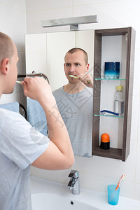 年轻帅哥在浴室里刷牙看镜子图片