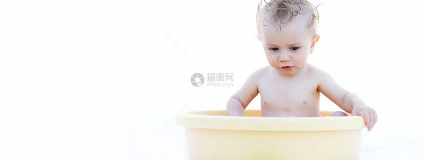 可爱的白宝独自在黄浴盆玩耍图片
