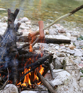 在山河边煮肉和香肠的户外篝火图片