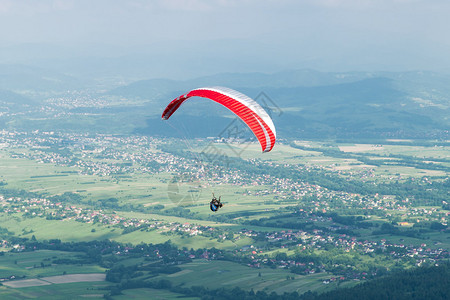 夏天滑翔伞飞过山中的村庄图片