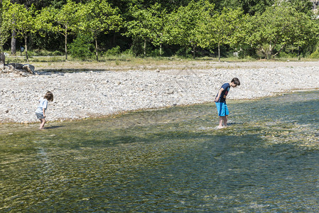 跨越充满石块的河流的儿童在西图片