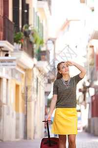 迷人的年轻女子走在目的地城市一条风景如画的狭窄街道上图片