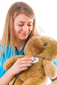 美丽的年轻儿科医生在一只泰迪熊的帮助下以有趣的方式介绍医疗程序图片
