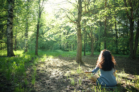 在夏日绿色森林中冥想的年轻女孩图片