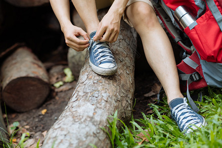 男徒步旅行者在夏季森林系鞋带图片