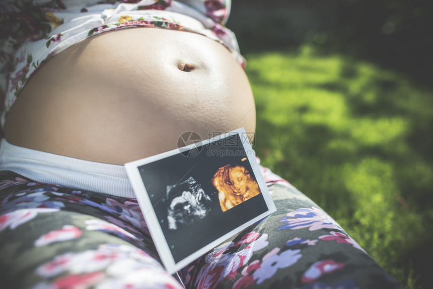 孕妇拿着子宫的照片花园里的日光图片