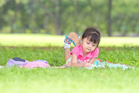 亚洲女孩在户外躺在草地上画图片