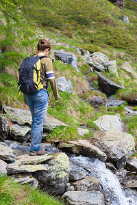 山上有背包穿过小溪流的女远足者在意大利阿尔卑斯图片